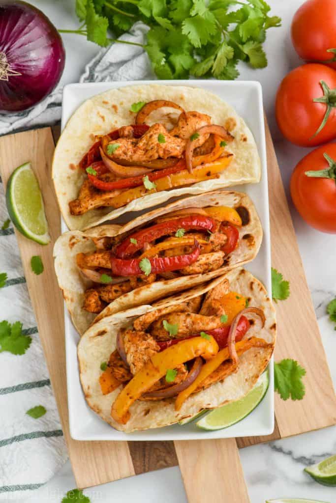 overhead view of three baked chicken fajitas in on a white plate