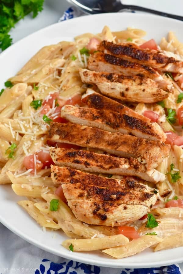 a close up of a plate of creamy cajun chicken pasta with the chicken blackened and cut up on a bed of pasta