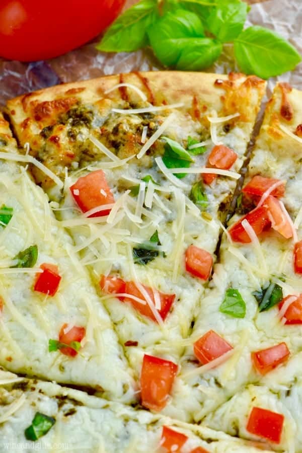 up close view of easy pesto pizza recipe garnished with cheese and tomatoes