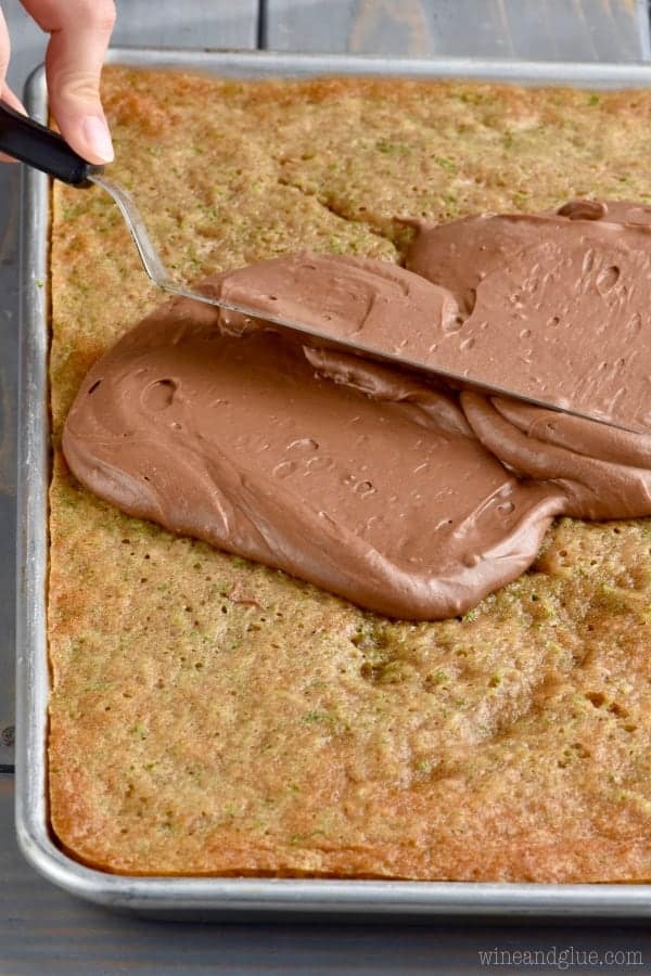 Spreading chocolate frosting on zucchini cake.