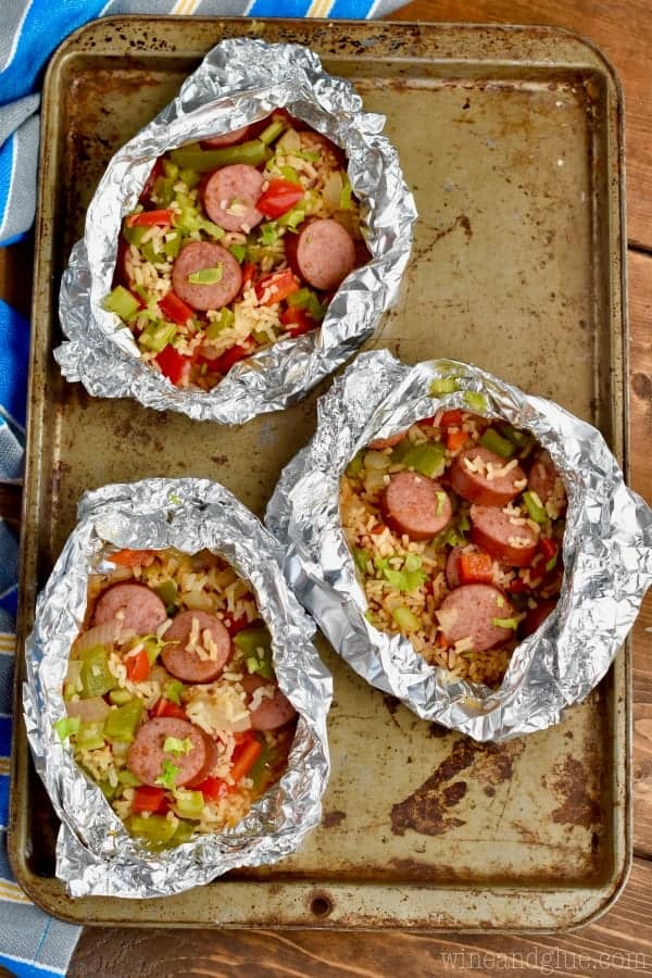 Three Jambalaya Foil packets are on a baking sheet – all opened up with the filling. 