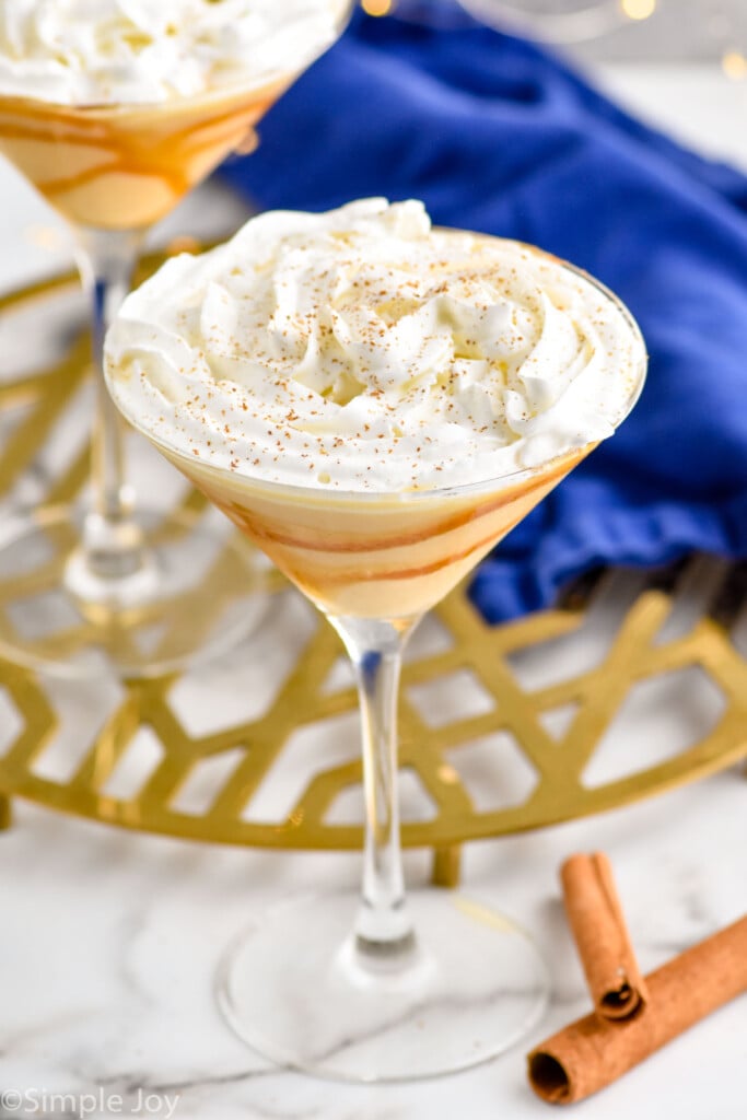 close view of an eggnog martini topped with whipped cream and cinnamon shavings