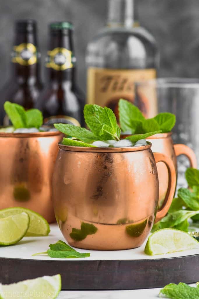 moscow mule ingredients behind a copper mug filled with a moscow mule, mint, and lime