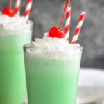 two tall tumblers filled with shamrock shakes, topped with whipped cream and a cherry