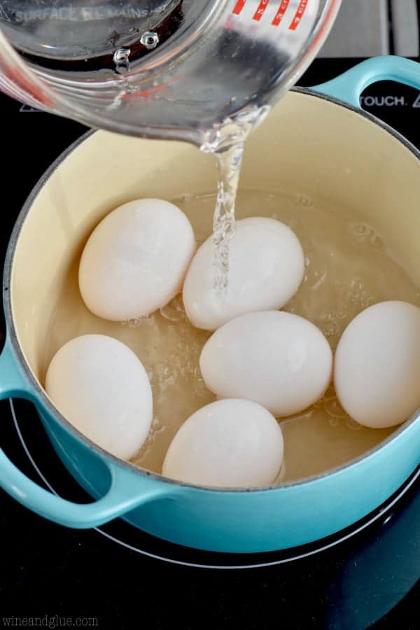 pouring water over 6 eggs in a small pot