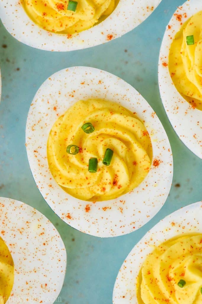 close up of a deviled egg that has been garnished with chives and paprika and piped with a star tip