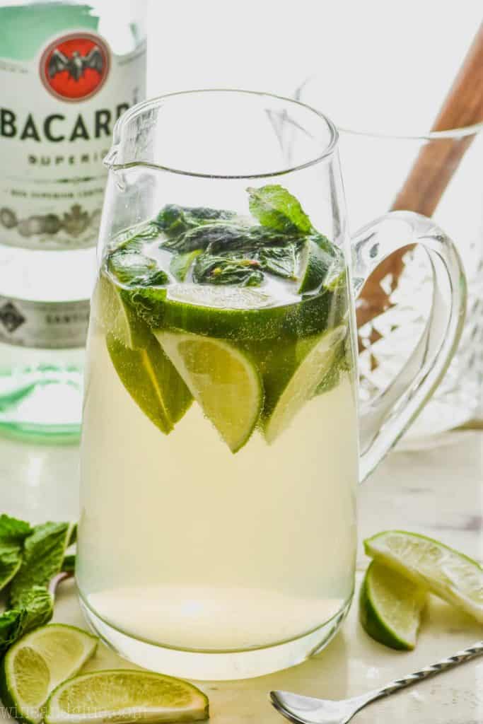 pitcher of mojito sangria recipe with limes and mint and a bottle of bacardi in the background