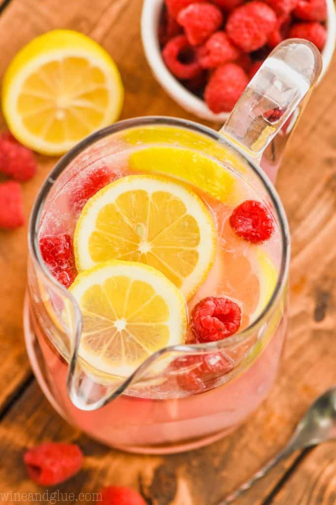 overhead view of a pitcher of pink lemonade vodka punch floating with fresh lemons and fresh raspberries