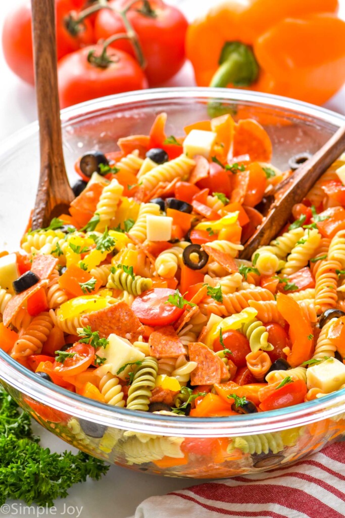 italian pasta salad in a large clear bowl garnished with parsley