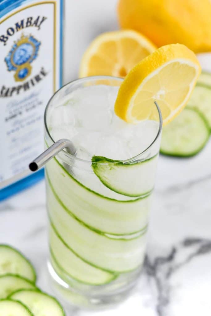 overhead view of a high ball glass with cucumber lemon gin and tonic and garnished with a lemon slice