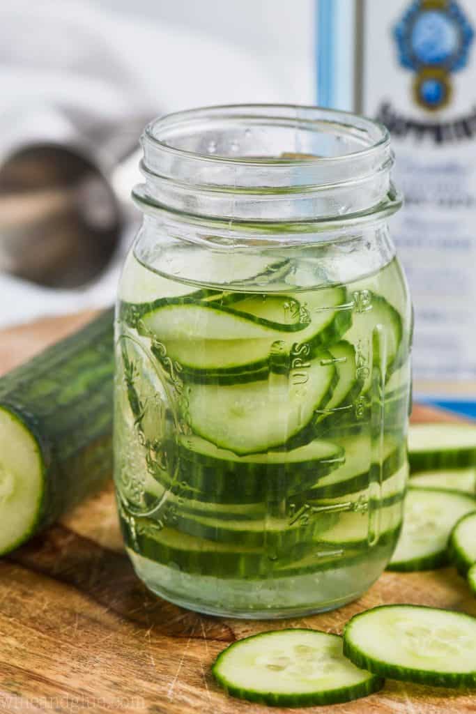 front view of a mason jar filled with sliced cucumbers and gin to make cucumber infused gin