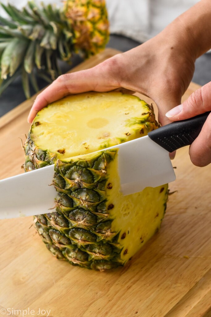 a pineapple on a cutting board with the skin being cut off
