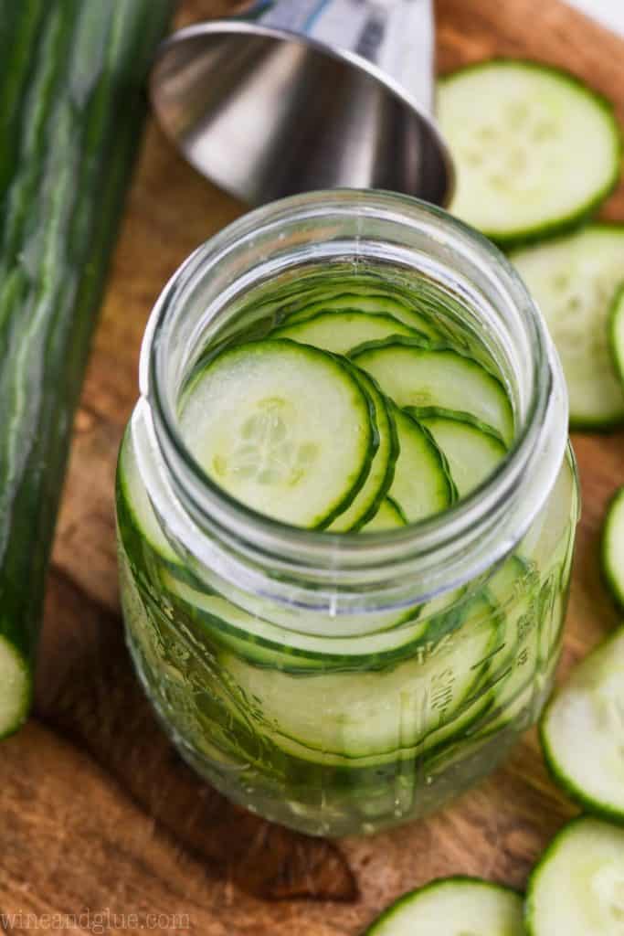 overhead view of a mason jar full of sliced cucumbers and gin to make cucumber flavored gin