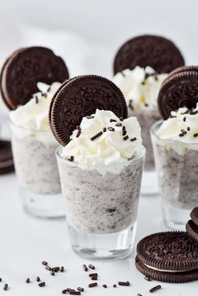 cookies and cream pudding shots in four glasses garnished with ores and whipped cream