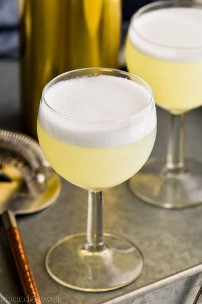 small goblet of gin fizz with a frothy egg white top on a metal tray