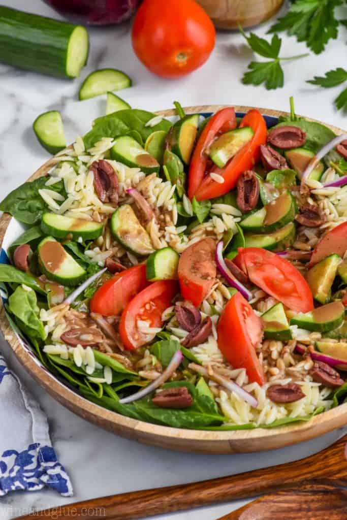 greek orzo pasta salad in a bowl with creamy balsamic dressing on it