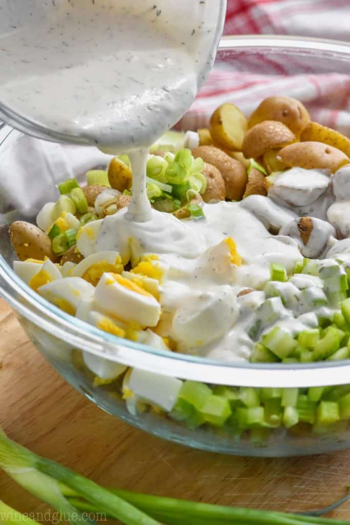 pouring dressing on potato salad