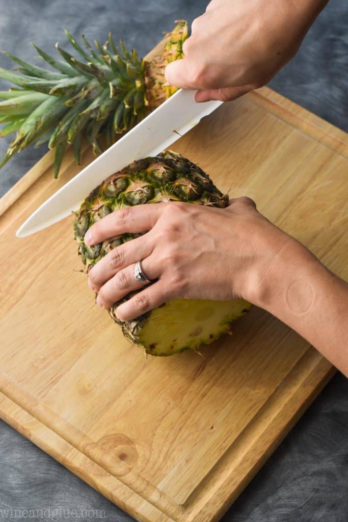 a pineapple on a cutting board with the bottom being cut off