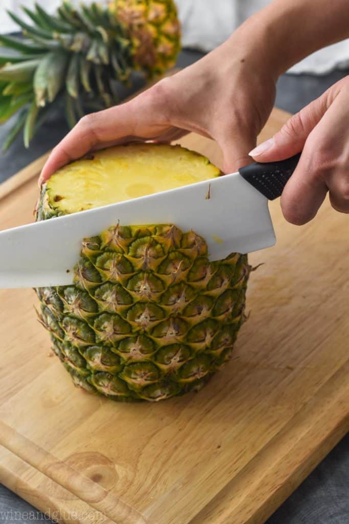 a pineapple on a cutting board with the skin being cut off