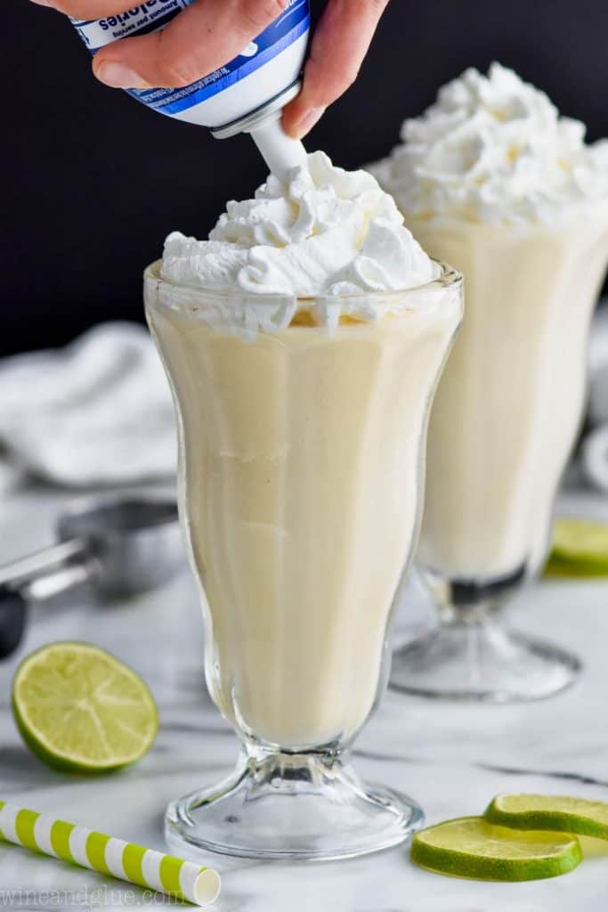 garnishing a boozy margarita milkshake with whipped cream