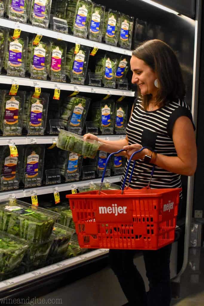 woman holding baby spinach in a grocery store