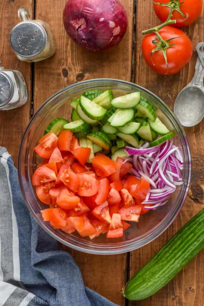 overhead view of cucumbers, tomatoes, and onions in a bowl for a cucumber and tomato salad