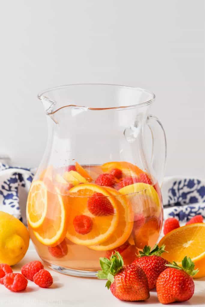 pitcher of easy white wine sangria recipe with raspberries, strawberries, oranges, and lemons