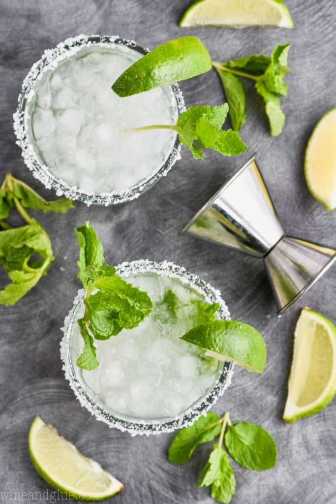 overhead view of two tumblers of mojito margaritas rimmed with salt