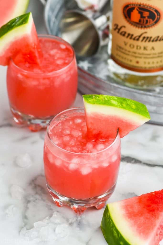 two tumblers of watermelon vodka tonic next to a metal tray