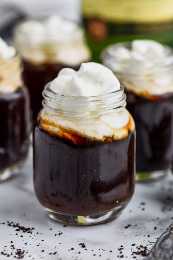 up close video of an irish coffee shot topped with whipped cream with more irish coffee shots in the background