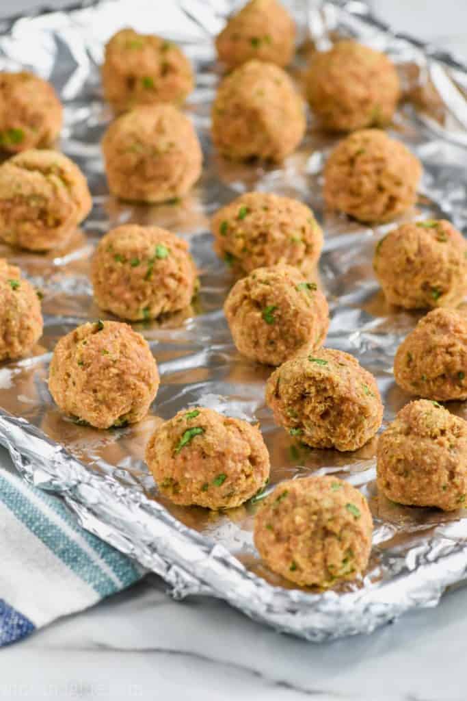 baked turkey meatballs lined up on a baking sheet