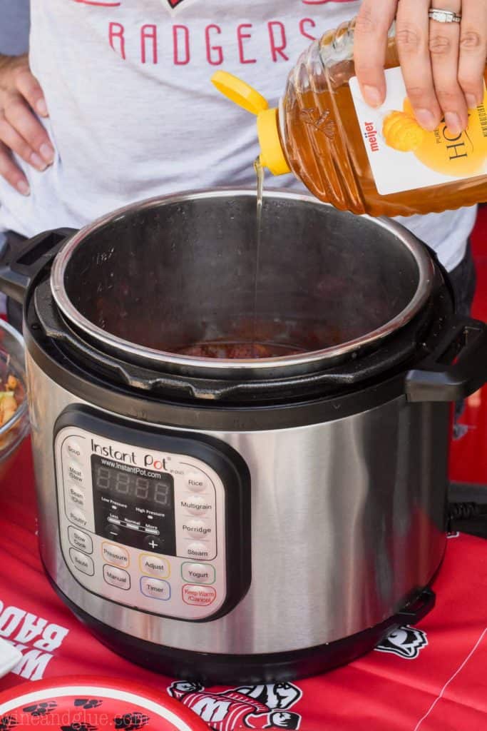 woman pouring honey into an instant pot full of cocktail meatballs