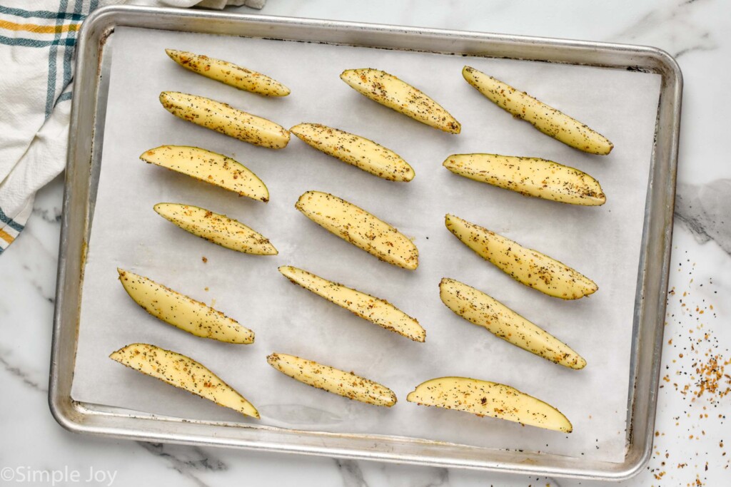 cut potatoes that have been seasoned on a rimmed baking sheet ready to be baked