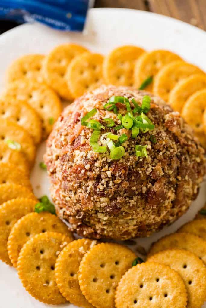 The Barbecue Bacon Cheese Ball is surrounded by Ritz Crackers and topped with chives. 