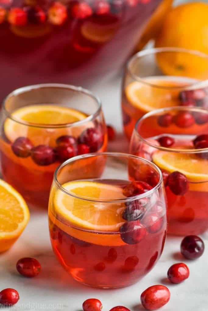 cups of christmas punch with oranges and cranberries floating in it 