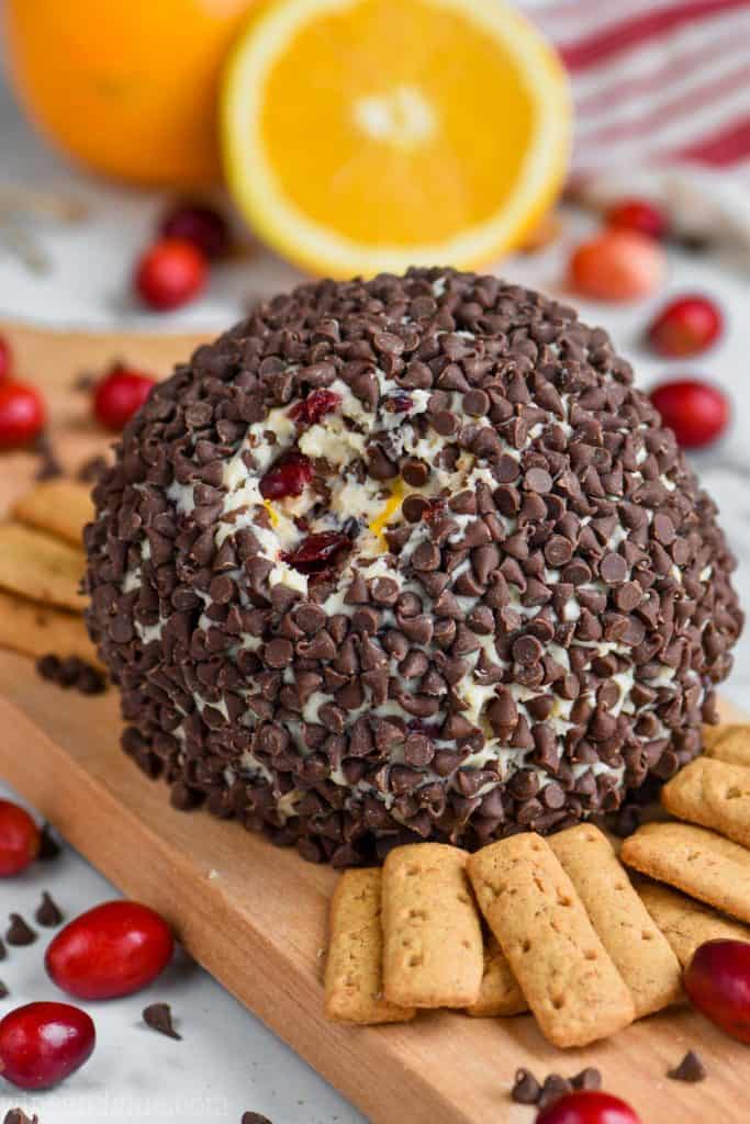 chocolate chip coated cranberry orange cheese ball recipe on a cutting board with crackers