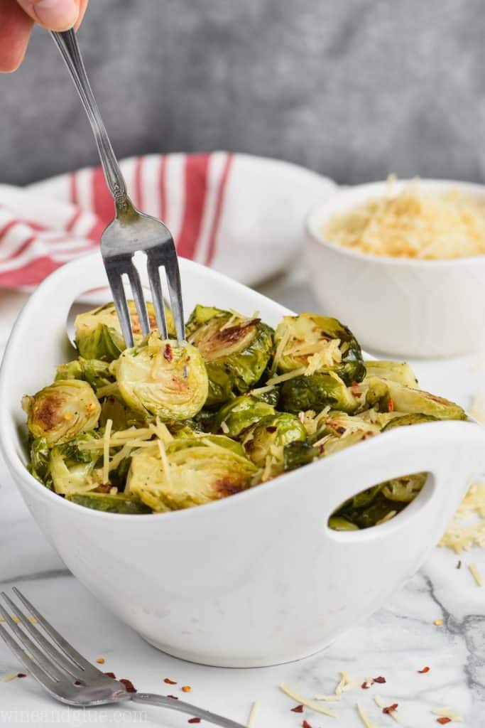 fork getting a brussels sprout out of a bowl of crispy roasted brussels sprouts