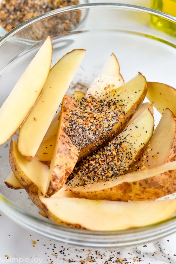 cut up potatoes in a bowl seasoned to make easy baked potato wedges