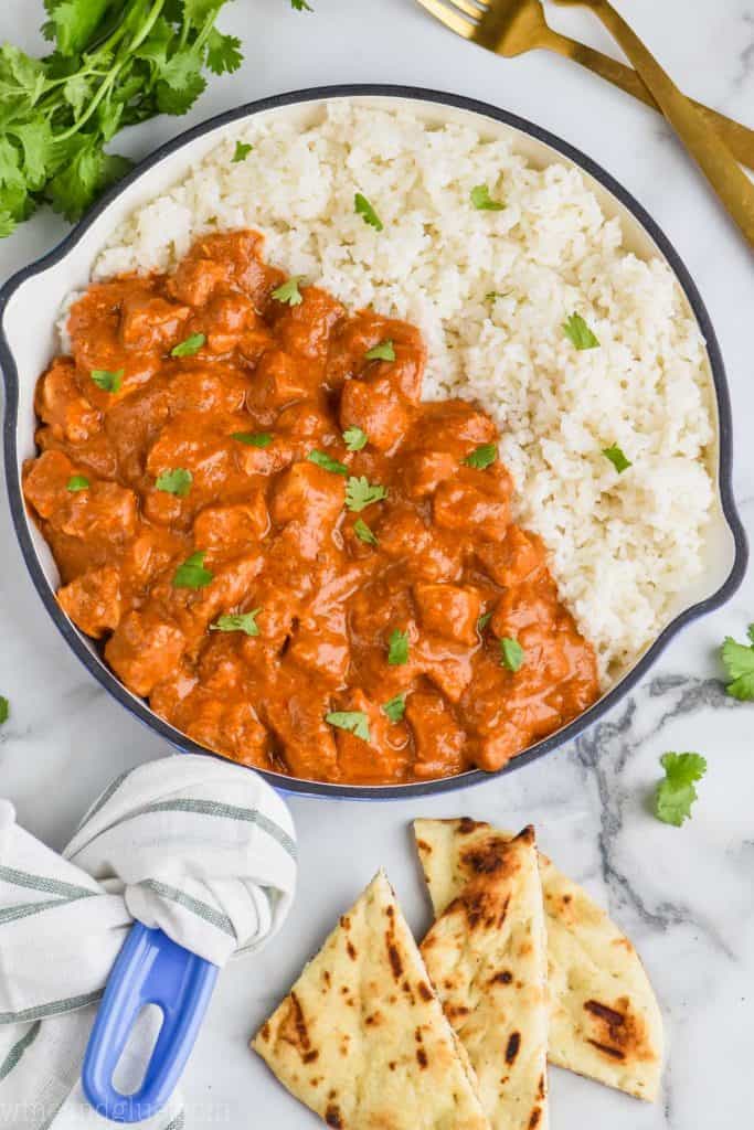 overhead view of pan of butter chicken recipe with rice and cilantro 