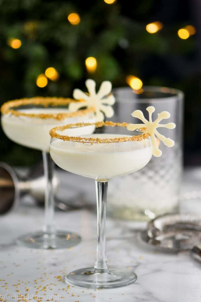 two christmas martinis garnished and in front of holiday lights