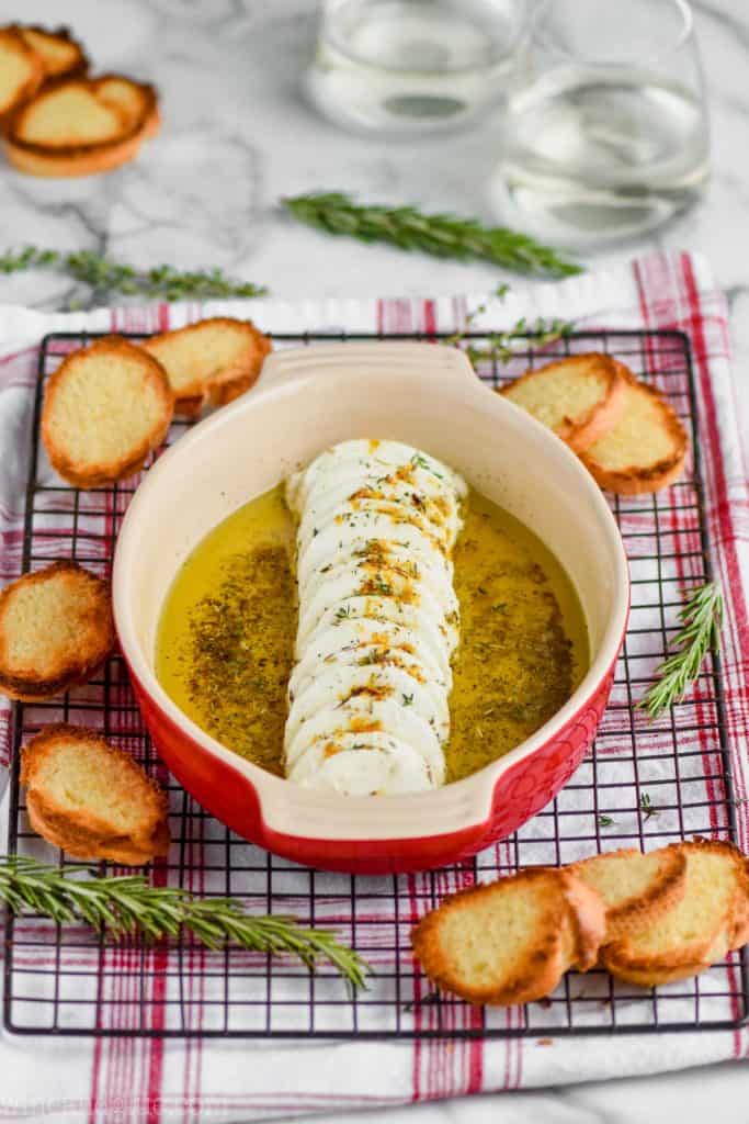 easy goat cheese appetizer in a small baking dish with toasted baguettes around it