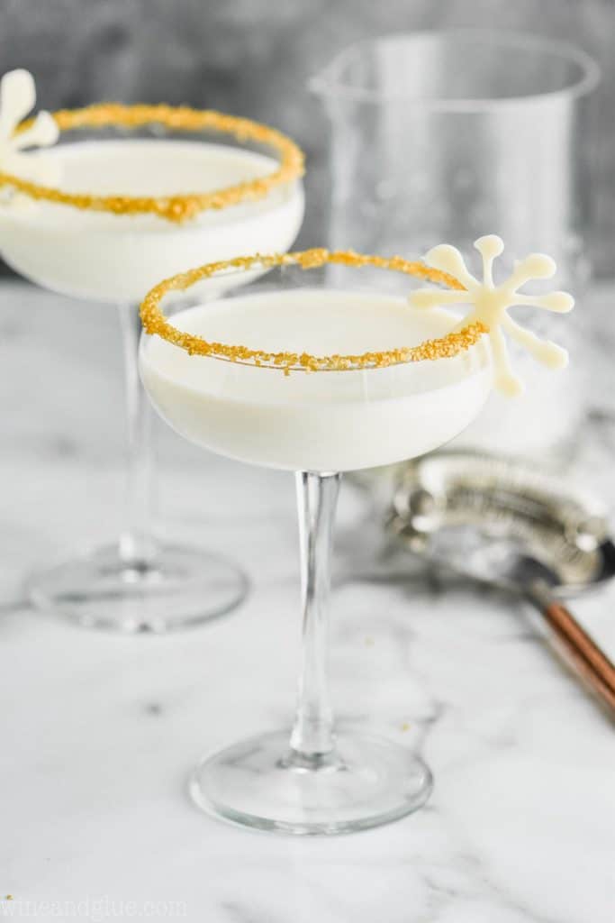 two holiday martinis for christmas in glasses garnished with gold sugar