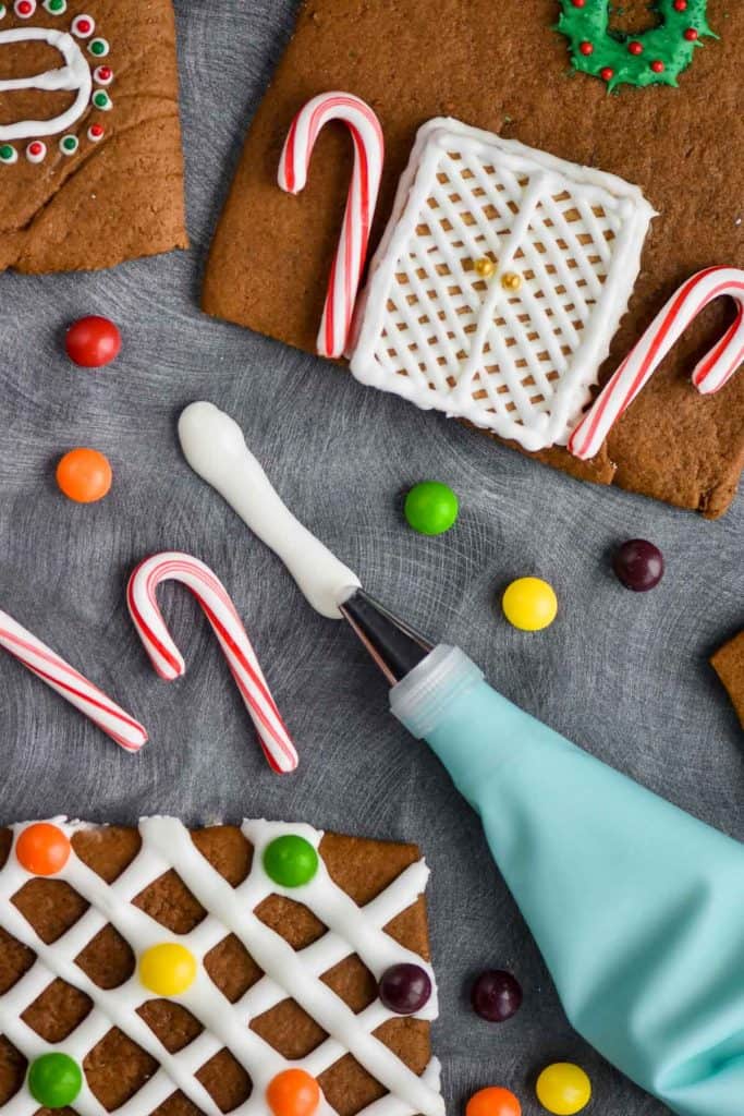 royal icing for gingerbread houses being piped by pieces of gingerbread