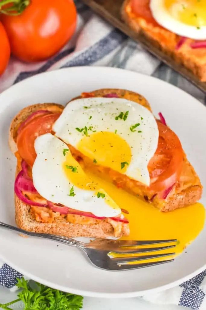 a cut open fried egg on hummus toast