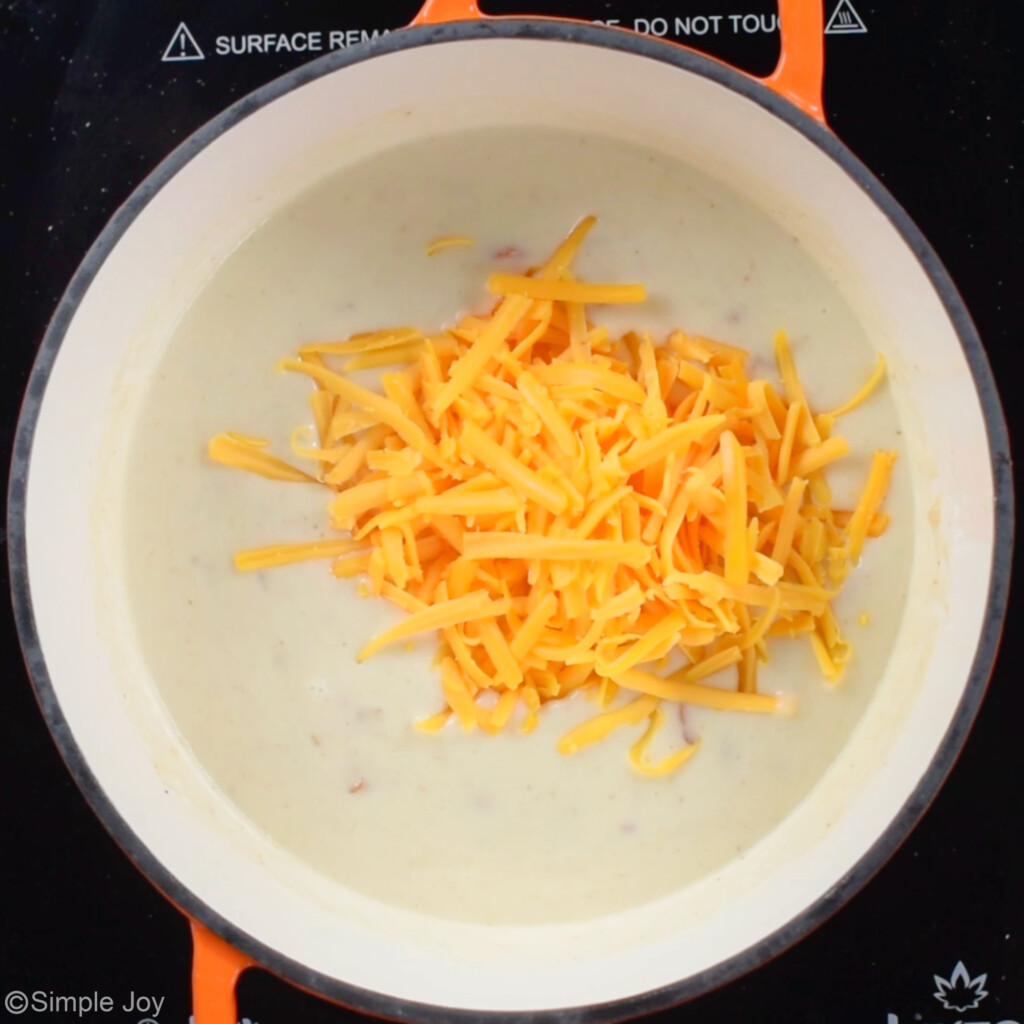 adding cheese to a creamy mixture in a small sauce pan