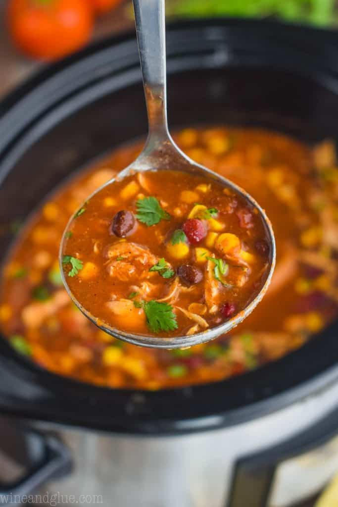 a ladle full of taco soup that has been dished up from a slow cooker