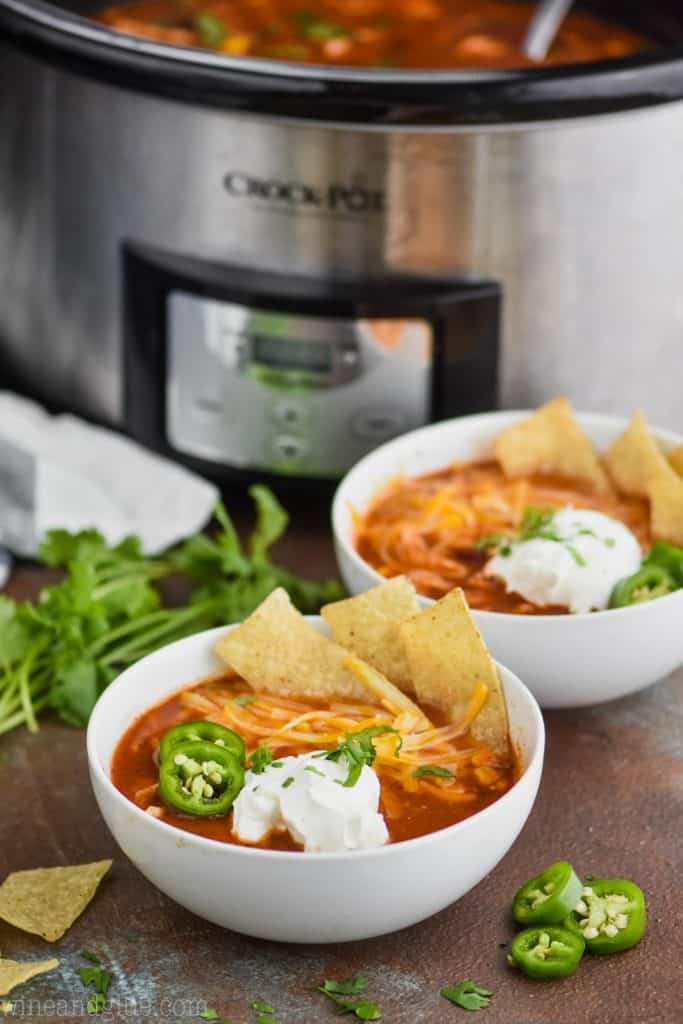 two bowls of easy chicken tortilla soup in front of a crock pot