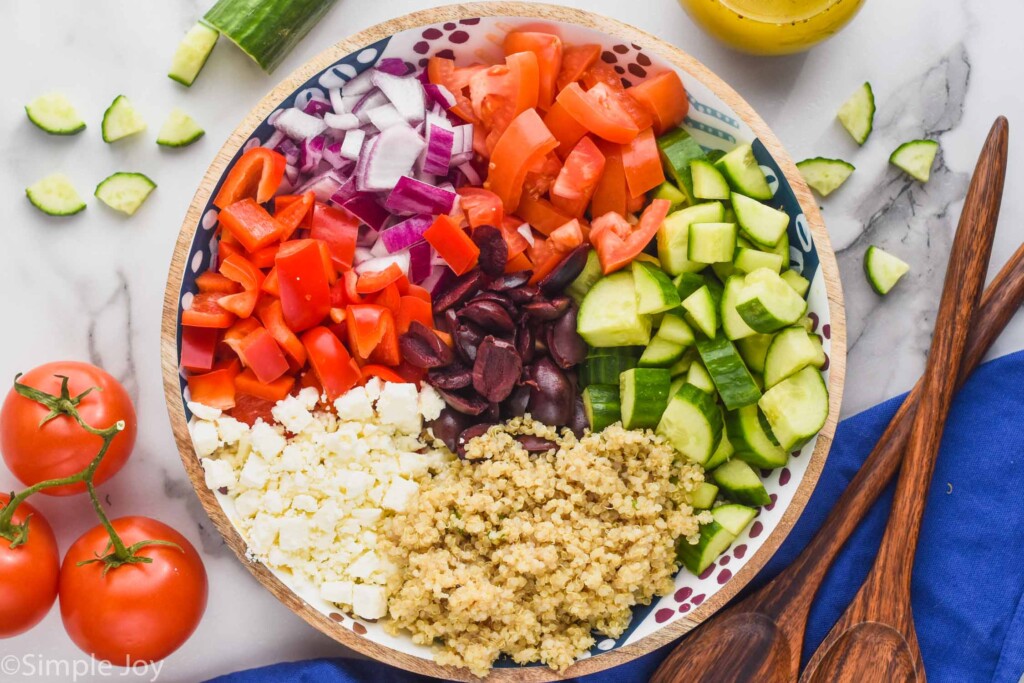 greek quinoa salad ingredients in a bowl separated by ingredients