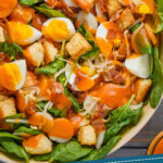 pinterest graphic of a spinach salad with dressing over it, says: a family favorite spinach salad simplejoy.com