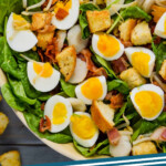 pinterest graphic of spinach salad overhead of a spinach salad with hard boiled eggs, bean sprouts, and bacon says: "spinach salad simplejoy.com"